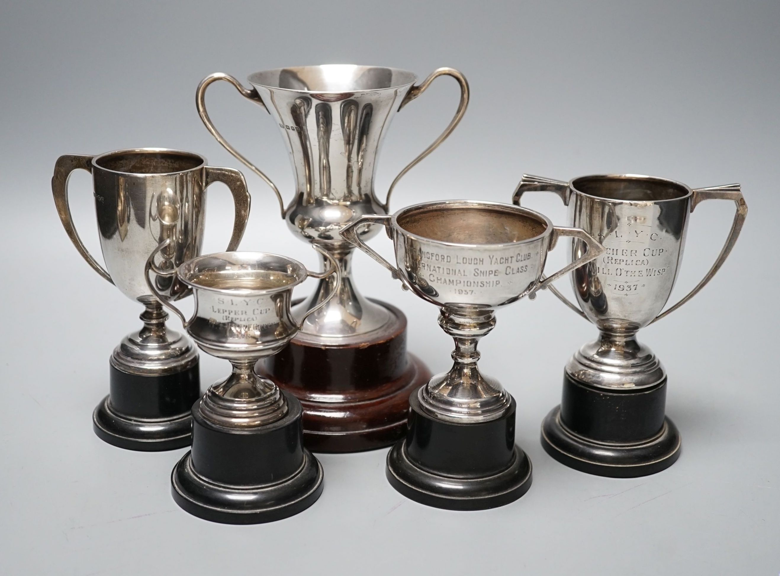 Five assorted 1920's/1930's silver two handled presentation trophy cups, all with engraved inscriptions and all with stands, largest 11.8cm.